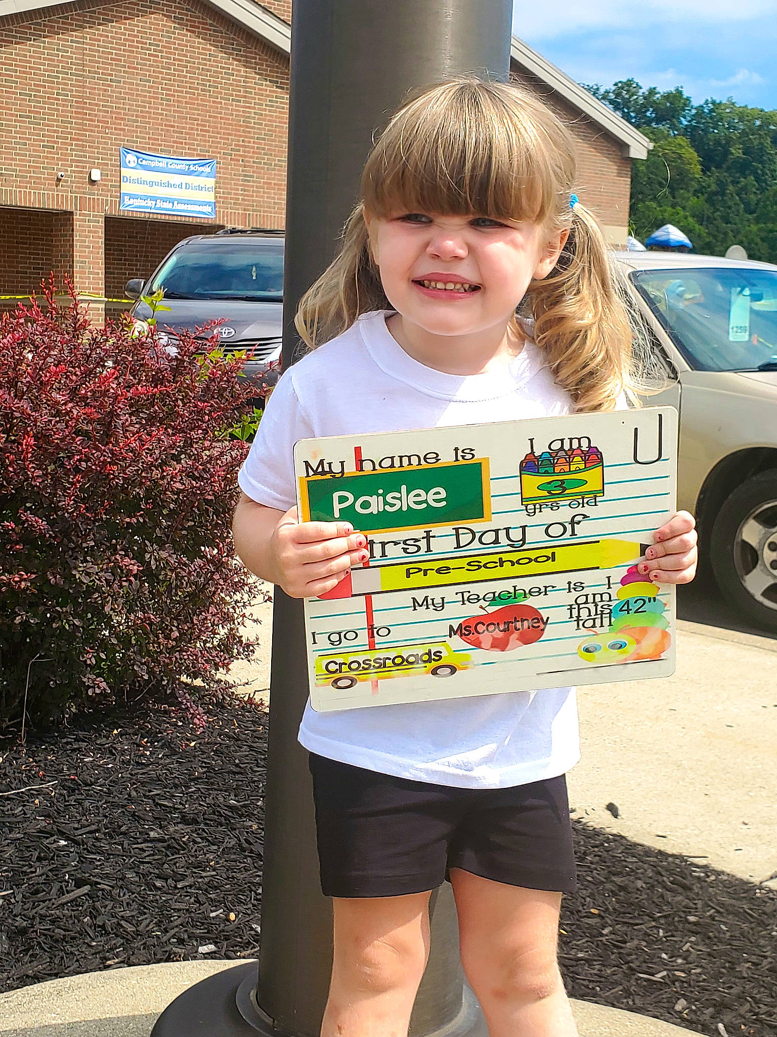 Paislee is registered to the contest to win money with this photo: asphalt, blond, car, child, event, fun, grass, hairstyle, human_leg, joy, motor_vehicle, person, plant, recreation, shorts, sky, sleeve, summer, t_shirt, thigh