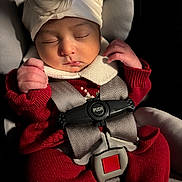 Ciara is registered to the contest to win money with this photo: baby, sleeping, car_seat, red_clothing, white_hat, infant, safety_harness, close_up, cute, peaceful, child, newborn, portrait, indoors, soft_lighting, hands, face, cozy, resting, adorable