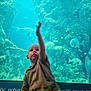 aquarium, blue, casual_clothing, child, curious, exploration, fish, glass, indoor, marine_life, nature, reaching, rocks, sea_creatures, sitting, tank, toddler, underwater, water, young_child