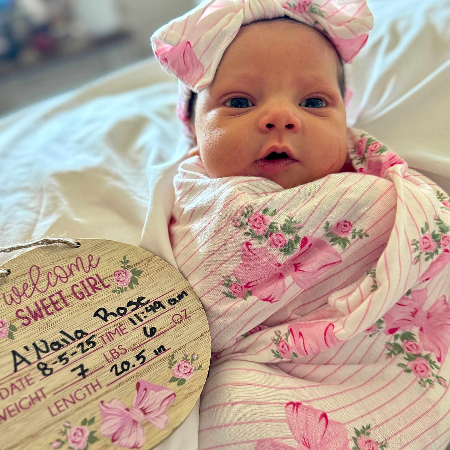 Anaila is registered to the contest to win money with this photo: baby, bed, birth_details, blanket, child, closeup, cute, floral, handwritten, headband, indoors, infant, newborn, person, pink, plaque, portrait, sleeping_area, soft, wrapped
