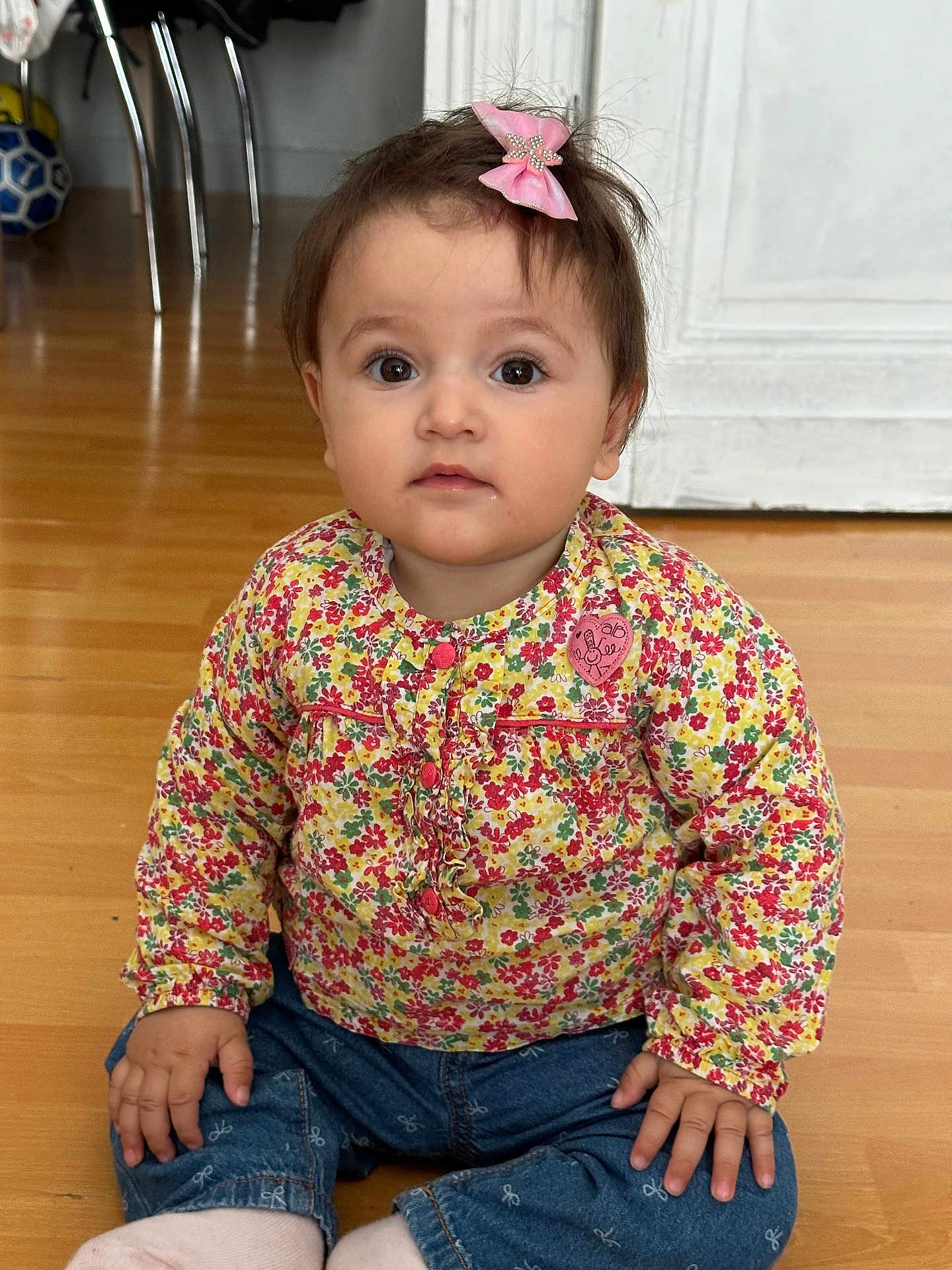 Vanessa a rejoint le concours — aidez-le/la à gagner de superbes lots ! child, toddler, baby, hair_bow, pink_bow, floral_shirt, jeans, sitting, hardwood_floor, big_eyes, portrait, hands, socks, indoor, door, chair, soccer_ball, curious_expression, cheeks, cute