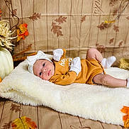 Jaslene is registered to the contest to win money with this photo: baby, infant, blanket, pumpkin, autumn, fall, leaves, headband, mittens, socks, brown_clothing, white_fluffy, decorations, wooden_floor, cute, lying_down, portrait, cozy, holiday_theme, seasonal
