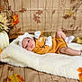 baby, infant, blanket, pumpkin, autumn, fall, leaves, headband, mittens, socks, brown_clothing, white_fluffy, decorations, wooden_floor, cute, lying_down, portrait, cozy, holiday_theme, seasonal