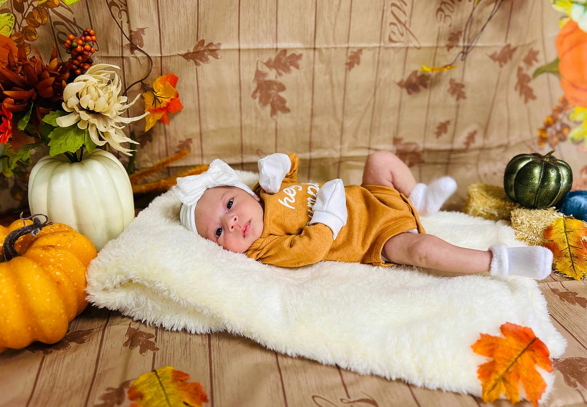 Jaslene is registered to the contest to win money with this photo: baby, infant, blanket, pumpkin, autumn, fall, leaves, headband, mittens, socks, brown_clothing, white_fluffy, decorations, wooden_floor, cute, lying_down, portrait, cozy, holiday_theme, seasonal