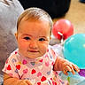 baby, child, infant, heart_pattern, dress, balloons, indoor, couch, smiling, happy, cute, chubby_cheeks, person, portrait, seated, colorful, playtime, soft_light, young, fun