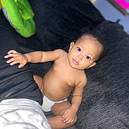 Ivy joined the competition — help win amazing prizes! baby, infant, child, diaper, couch, indoor, curious, skin, face, hand, sitting, looking, expression, wide_eyes, blurred_background, black_hair, person, young, casual, relaxed