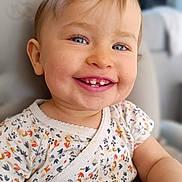 Léonie participe au concours pour gagner de l'argent avec cette photo : arm, baby_teeth, blue_eyes, blurred_background, chair, child, clothing, cute, face, floral_shirt, happy, indoor, infant, person, portrait, seated, skin, smile, toddler, young_child
