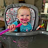 baby, high_chair, face, food, spoon, smile, blue_clothing, pink_food, messy, happy, indoor, child, person, seat, table, reflection, furniture, home, cute, portrait