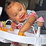 baby, toddler, child, walker, toy, snack, cheese_puffs, smiling, happy, indoor, clothing, hair_bun, face, hand, seat, playful, colorful, person, infant, cute
