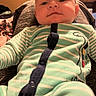 baby, infant, child, portrait, sitting, car_seat, pajamas, striped_clothing, green_clothing, indoor, home, living_room, television, furniture, head, face, serious_expression, looking_at_camera, close_up, photography