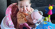 Evelyn is registered to the contest to win money with this photo: baby, child, infant, smiling, sitting, activity_center, jumper, toy, plush_elephant, butterfly_toy, colorful, indoor, living_room, couch, blanket, playtime, portrait, face, happy, baby_clothing
