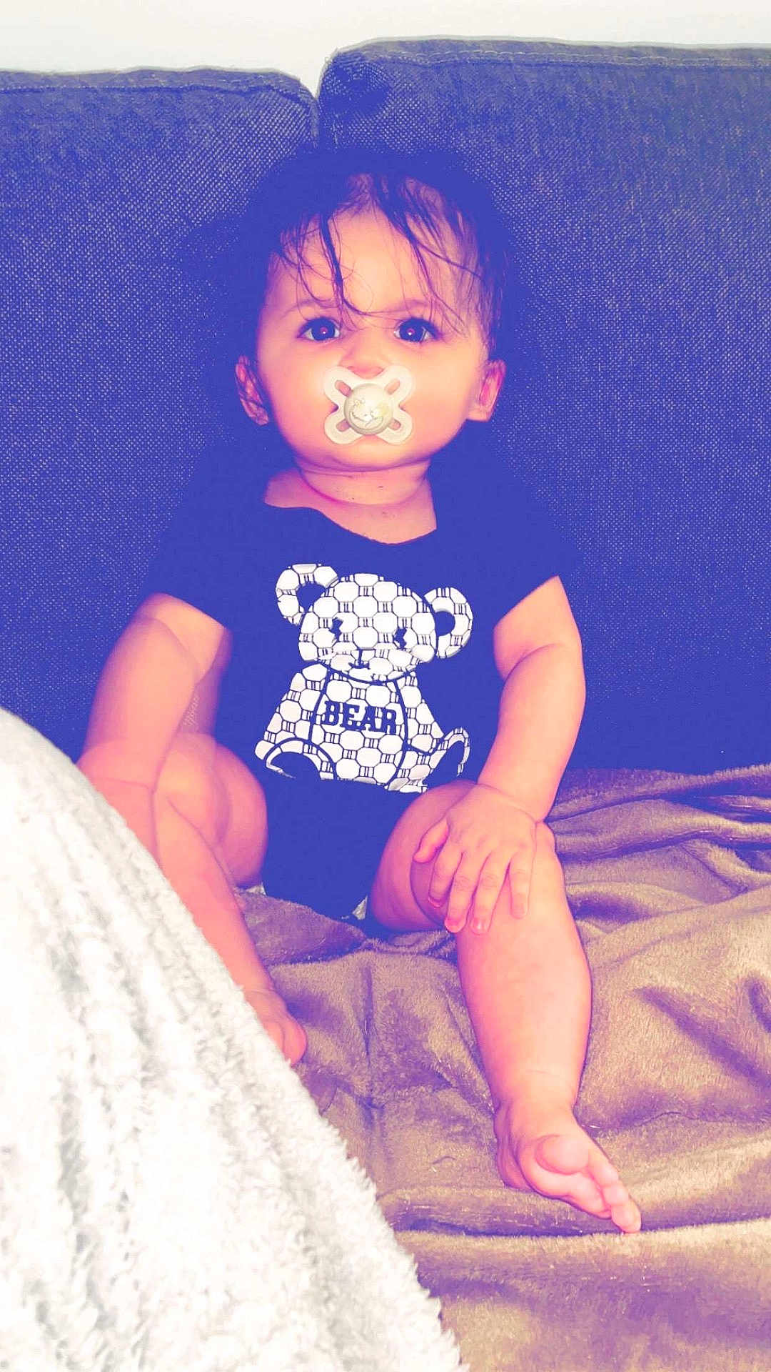 Ilyess participe au concours pour gagner de l'argent avec cette photo : baby, pacifier, couch, blanket, onesie, bear_graphic, child, indoors, sitting, cute, toddler, comfort, furniture, soft_texture, portrait, young_child, infant, cozy, relaxed, clothing