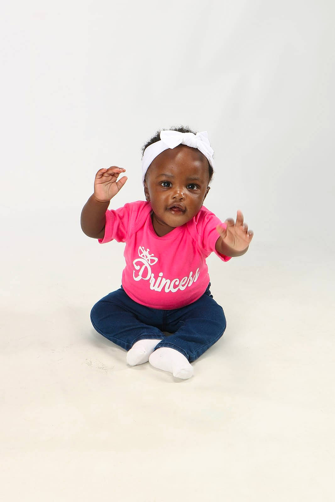 Chelsea is registered to the contest to win money with this photo: baby, baby_toddler_clothing, child, face, gesture, happy, head, knee, leg, magenta, person, physical_fitness, recreation, shirt, sitting, sleeve, smile, sportswear, t_shirt, thigh