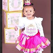 Phoenix is registered to the contest to win money with this photo: toddler, birthday, princess, pink_tutu, crown, blocks, one, smiling, child, studio, portrait, celebration, happy, fashion, footwear, white_shirt, gold_accents, cute, fun, posing