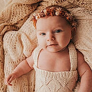 Esmée participe au concours pour gagner de l'argent avec cette photo : baby, baby_girl, child, closeup, cozy, cute, flower_crown, headband, indoors, infant, knitted_blanket, knitwear, newborn, peaceful, portrait, resting, smiling, soft_lighting, texture, warm_colors