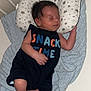 baby, newborn, sleeping, crib, pillow, blanket, clothing, infant, cute, peaceful, indoors, resting, child, person, star_pattern, knitted_blanket, foot, hand, black_outfit, sleep