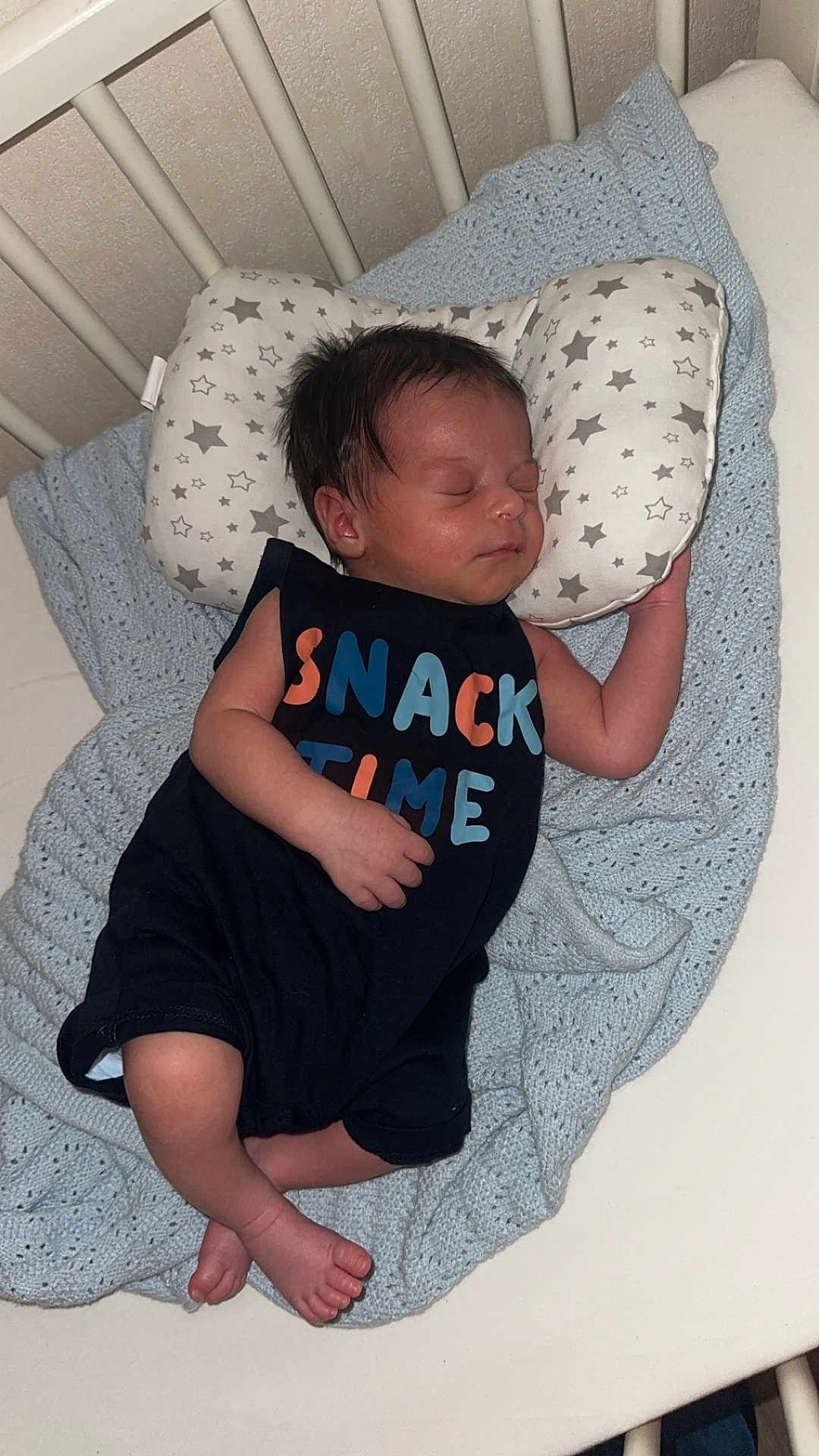 Zayd participe au concours pour gagner de l'argent avec cette photo : baby, newborn, sleeping, crib, pillow, blanket, clothing, infant, cute, peaceful, indoors, resting, child, person, star_pattern, knitted_blanket, foot, hand, black_outfit, sleep