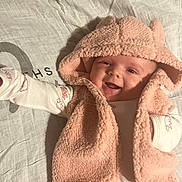 Ellena joined the competition — help win amazing prizes! baby, infant, smile, hood, pink, vest, clothing, lying_down, fabric, pattern, cute, happy, child, portrait, face, apparel, soft, warm, newborn, eyes