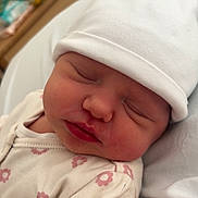 Myla joined the competition — help win amazing prizes! baby, newborn, sleeping, white_hat, onesie, floral_pattern, face, infant, closeup, peaceful, soft_skin, cute, child, portrait, resting, indoors, cozy, human, newborn_clothing, sleep