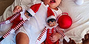 Evan David a rejoint le concours — aidez-le/la à gagner de superbes lots ! baby, infant, santa_hat, white_clothing, elf_doll, striped_clothing, red_and_white, plush_toy, reindeer_toy, christmas_decoration, red_ornament, blanket, floor_tiles, festive, holiday, cute, child, smiling, indoors, toy