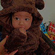 Xavier is registered to the contest to win money with this photo: baby, child, costume, brown, bear, hood, fluffy, cute, hand, indoor, toy, colorful, sitting, portrait, face, eyes, thumb, warm, soft, clothing