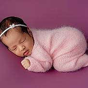 Ailani joined the competition — help win amazing prizes! newborn, baby, sleeping, pink, knitted, outfit, headband, face, closed_eyes, peaceful, soft, purple_background, infant, cute, portrait, cozy, small_hand, resting, child, studio
