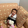 Ivanna joined the competition — help win amazing prizes! baby, child, smile, couch, patterned_fabric, toy, plush_toy, pacifier, happy, indoors, infant, clothing, cute, sitting, hand_gesture, decor, footwear, head, person, living_room