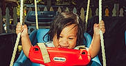 Jared joined the competition — help win amazing prizes! child, toddler, swing, playground, outdoor, sunlight, smiling, happy, ropes, blue_swing, red_safety_bar, barefoot, grass, trees, fence, summer, play, person, casual_clothing, daylight