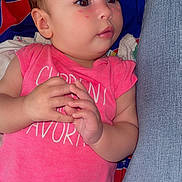 Chloe joined the competition — help win amazing prizes! baby, infant, pink_onesie, hands, face, cheeks, heart_marks, blue_jeans, patterned_background, lying_down, person, skin, cute, child, indoors, closeup, expression, young, portrait, casual