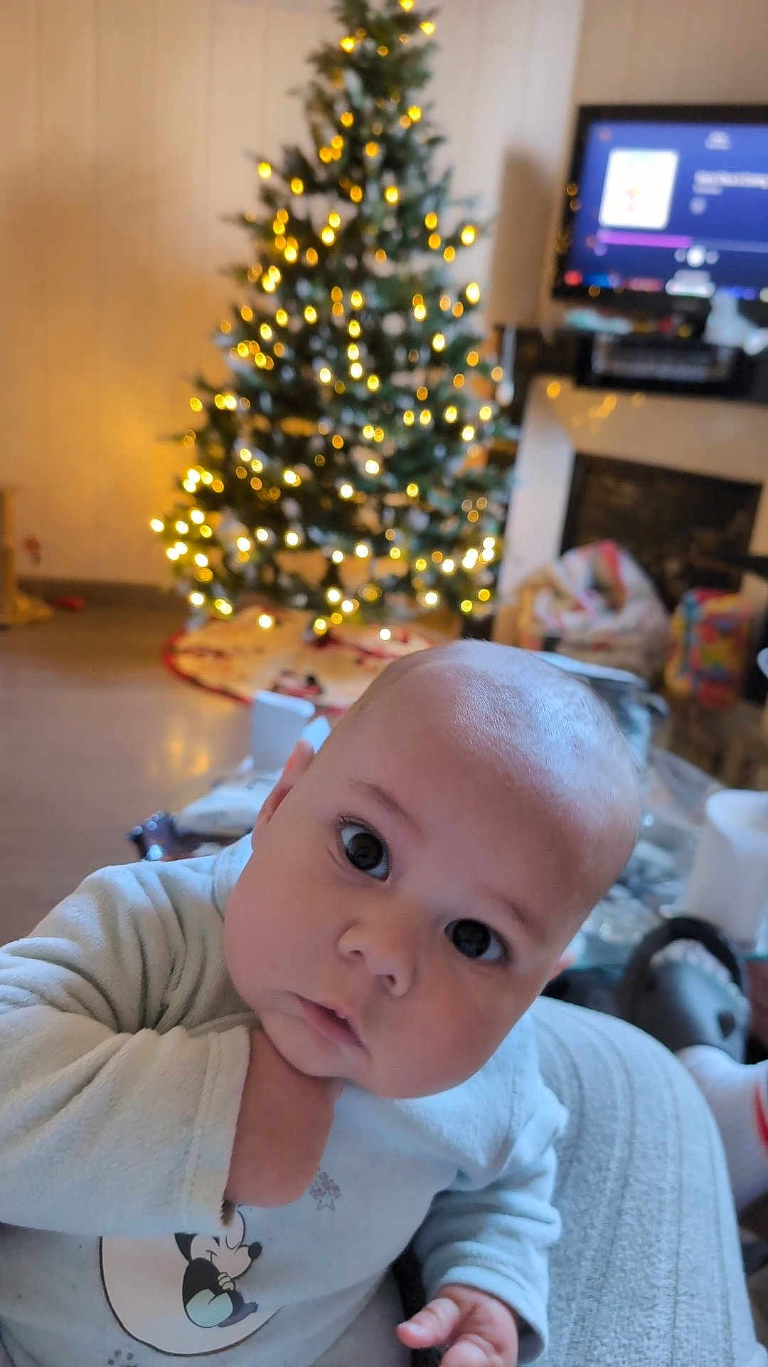 Kynaï participe au concours pour gagner de l'argent avec cette photo : baby, infant, child, face, expression, indoors, christmas_tree, lights, holiday, cozy, warm_lighting, clothing, person, portrait, curious, soft_focus, background_blur, home, festive, cute