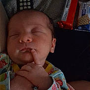 Lily joined the competition — help win amazing prizes! baby, sleeping, infant, blanket, onesie, colorful_clothing, hand, face, remote_control, snacks, dim_light, indoors, cute, peaceful, soft_texture, newborn, portrait, resting, child, cozy