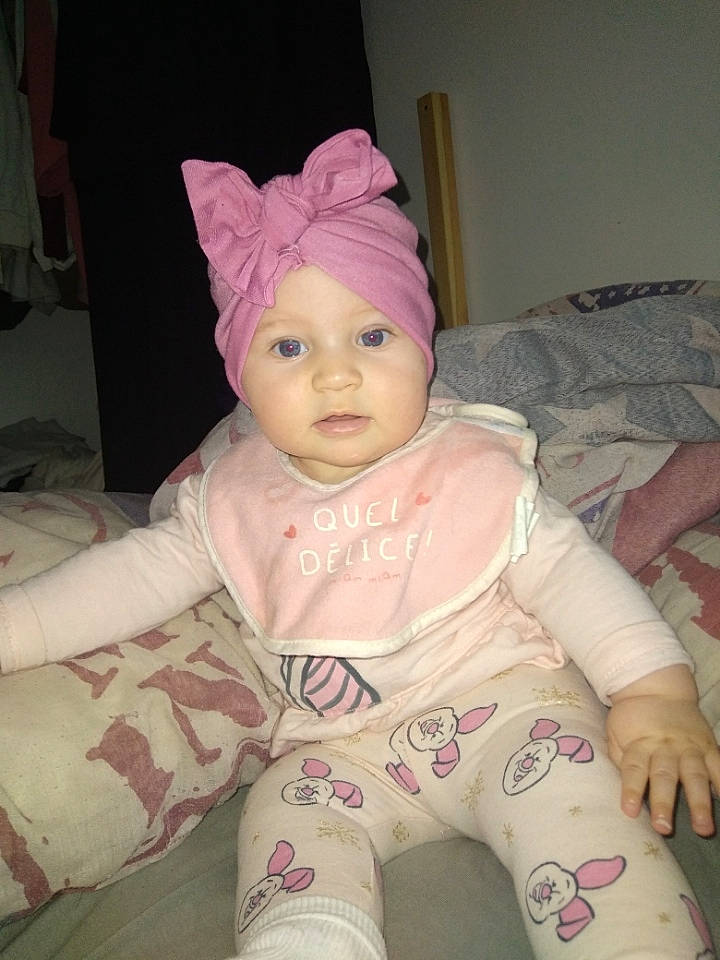 Inaya participe au concours pour gagner de l'argent avec cette photo : baby, baby_toddler_clothing, cap, cheek, child, comfort, eye, face, finger, headgear, headwear, human_body, knit_cap, linens, lip, magenta, person, pink, skin, sleeve
