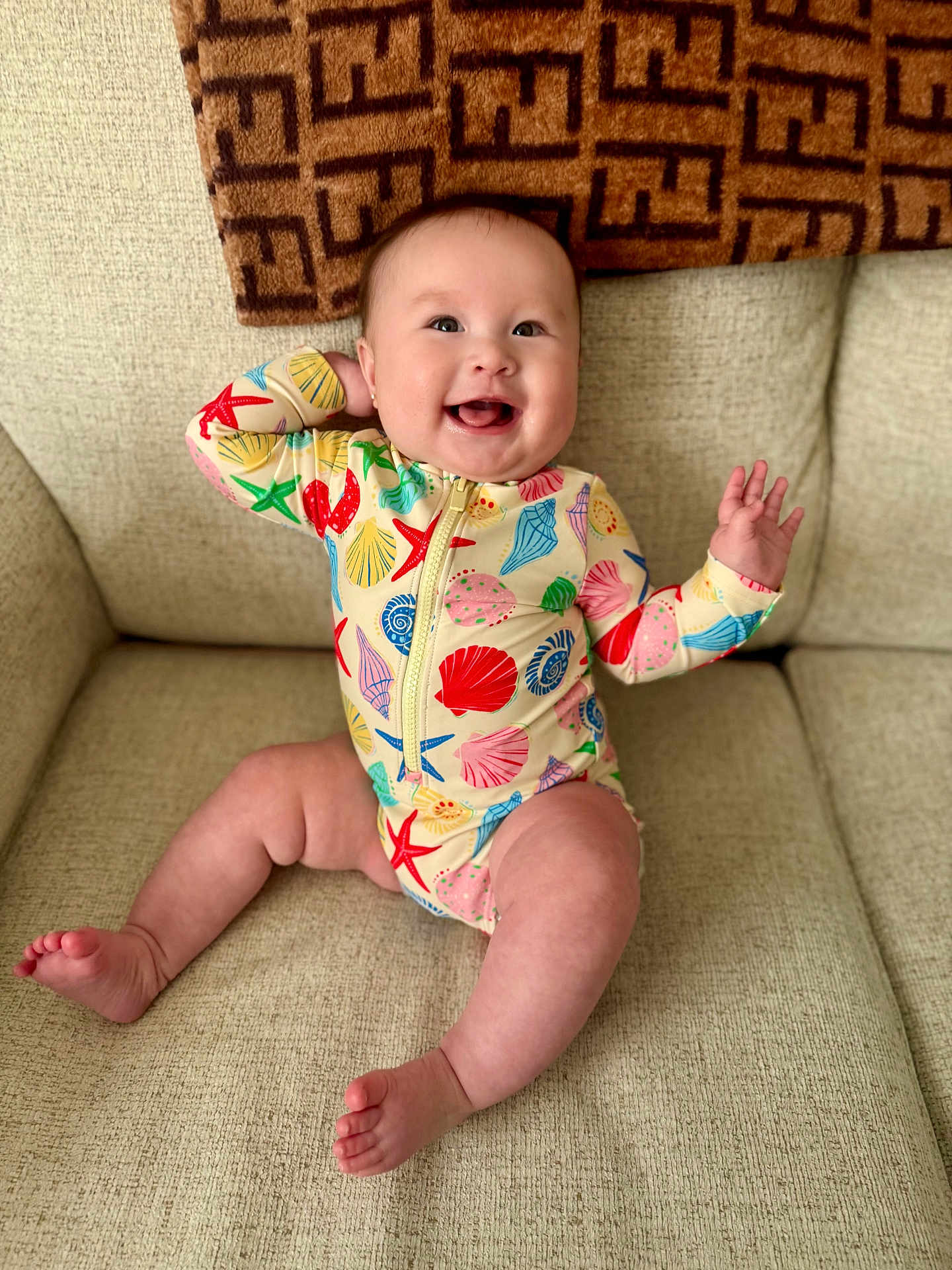 Adelaine Faythe is registered to the contest to win money with this photo: baby, infant, smiling, couch, onesie, seashell_pattern, starfish_pattern, happy, child, indoor, furniture, blanket, cheerful, cute, playful, skin, sitting, expression, home, portrait