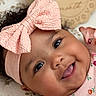 baby, infant, smiling, pink_bow, headband, floral_dress, tongue_out, cute, cheeks, lying_down, patterned_blanket, 6_months_sign, happy, portrait, closeup, face, child, adorable, indoor, soft_lighting