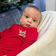 Oscar is registered to the contest to win money with this photo: baby, infant, red_clothing, blanket, christmas_tree, holiday, decorations, face, eyes, indoor, soft_texture, cozy, festive, child, portrait, candid, cute, seasonal, holiday_lights, winter