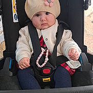 Jennah a rejoint le concours — aidez-le/la à gagner de superbes lots ! baby, baby_accessory, beaded_bracelet, blue_pants, car_seat, child, clothing, cute, face, floor, flower, hat, indoor, infant, jacket, person, pink_shoe, portrait, seatbelt, sitting