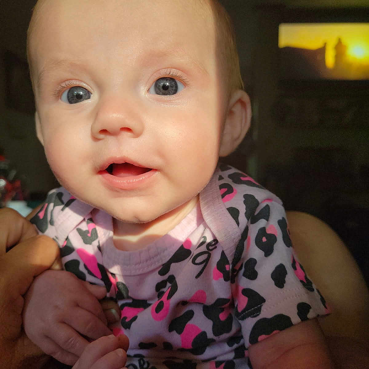 Jane joined the competition — help win amazing prizes! baby, blue_eyes, child, close_up, cute, expression, eye_contact, face, hand_holding, indoor, infant, newborn, patterned_clothing, person, pink_onesie, portrait, soft_skin, sunlight, tiny_fingers, young_child