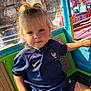 Maddy a rejoint le concours — aidez-le/la à gagner de superbes lots ! toddler, child, amusement_ride, carnival, blonde_hair, pony_tail, blue_shirt, sportswear, indoor, colorful, smiling, seat, toy_ride, face, person, daylight, playful, entertainment, fun, background