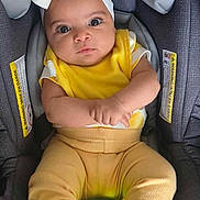 Amna joined the competition — help win amazing prizes! baby, child, car_seat, yellow_clothing, headband, toy, light_up_toy, socks, infant, cute, indoors, seatbelt, portrait, looking_up, hands, feet, playful, expression, sitting, comfort