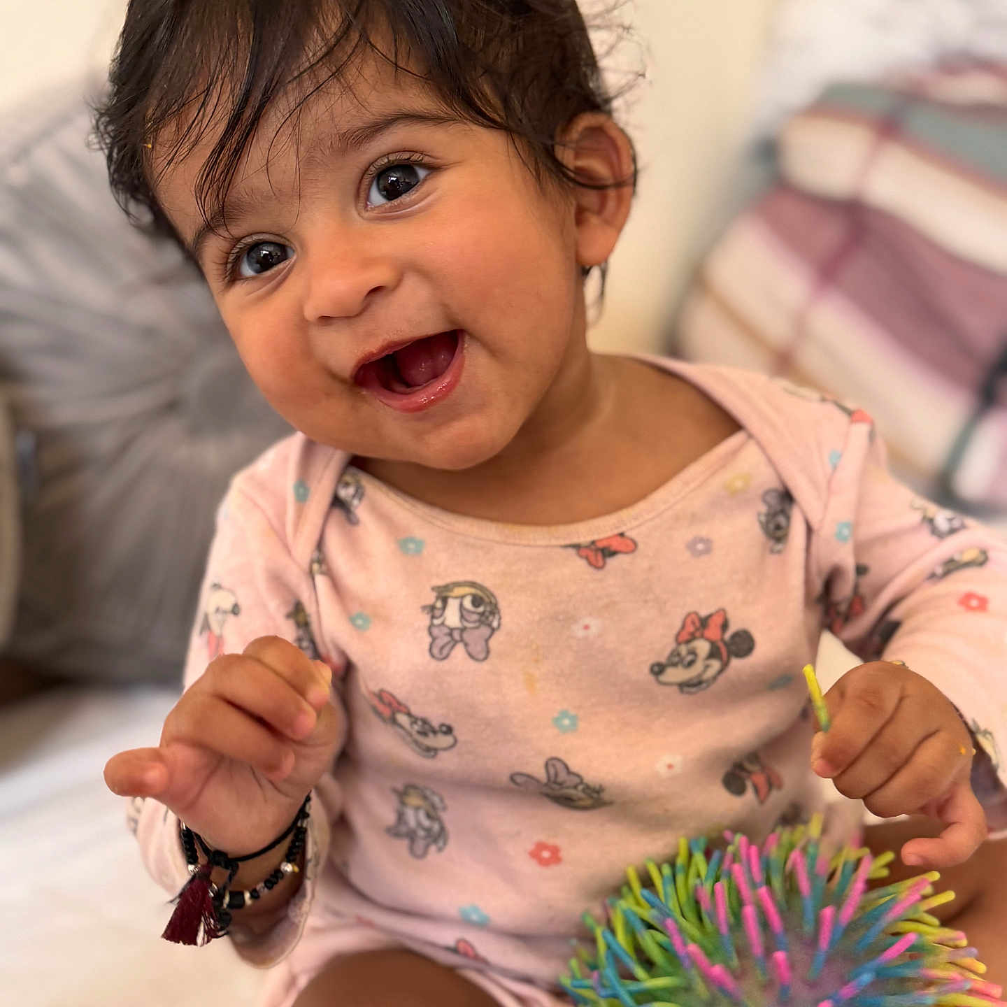 Sanvi joined the competition — help win amazing prizes! baby, ball, bed, child, clothing, colorful, cushion, cute, face, hair, happy, indoors, pajamas, pattern, person, playful, smiling, toddler, toy, young