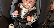 Ivy is registered to the contest to win money with this photo: baby, car_seat, infant, pacifier, headband, black, white_clothing, patterned_clothing, straps, safety_harness, floor, indoor, cute, small_feet, hands, face, eyes, expression, child, seat