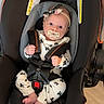 baby, car_seat, infant, pacifier, headband, black, white_clothing, patterned_clothing, straps, safety_harness, floor, indoor, cute, small_feet, hands, face, eyes, expression, child, seat