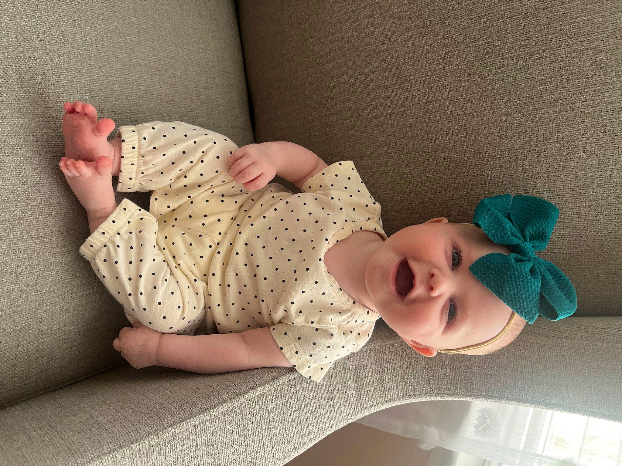 Lyla is registered to the contest to win money with this photo: baby_toddler_clothing, comfort, eyewear, facial_expression, finger, glasses, hat, headgear, human_leg, knee, leg, linens, neck, person, pink, skin, sleeve, smile, sunglasses, thigh