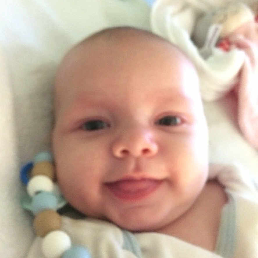 Raphael participe au concours pour gagner de l'argent avec cette photo : baby, beads, bed, blanket, closeup, clothing, comfort, cute, face, happy, head, indoors, infant, pacifier_clip, person, portrait, skin, smile, soft, young_child