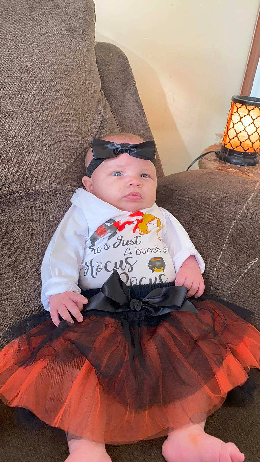 Nalani is registered to the contest to win money with this photo: baby, baby_toddler_clothing, beanie, bonnet, costume, costume_accessory, costume_hat, day_dress, embellishment, headwear, home_accessories, lamp, lampshade, lantern, lighting, lighting_accessory, orange, person, ruffle, throw_pillow