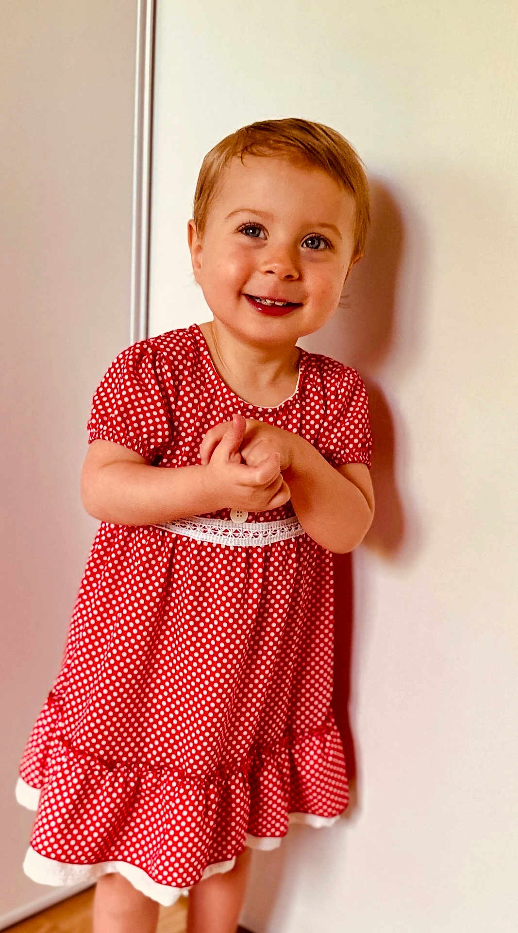 Mya participe au concours pour gagner de l'argent avec cette photo : toddler, child, smiling, red_dress, polka_dot, standing, happy, face, portrait, short_hair, indoor, human, cute, clothing, skin, person, childhood, joy, young, playful