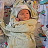 baby, towel, hood, infant, wrapped, playmat, toy, colorful, pattern, fist, lying_down, child, cute, soft, blanket, indoors, newborn, face, expression, comfort