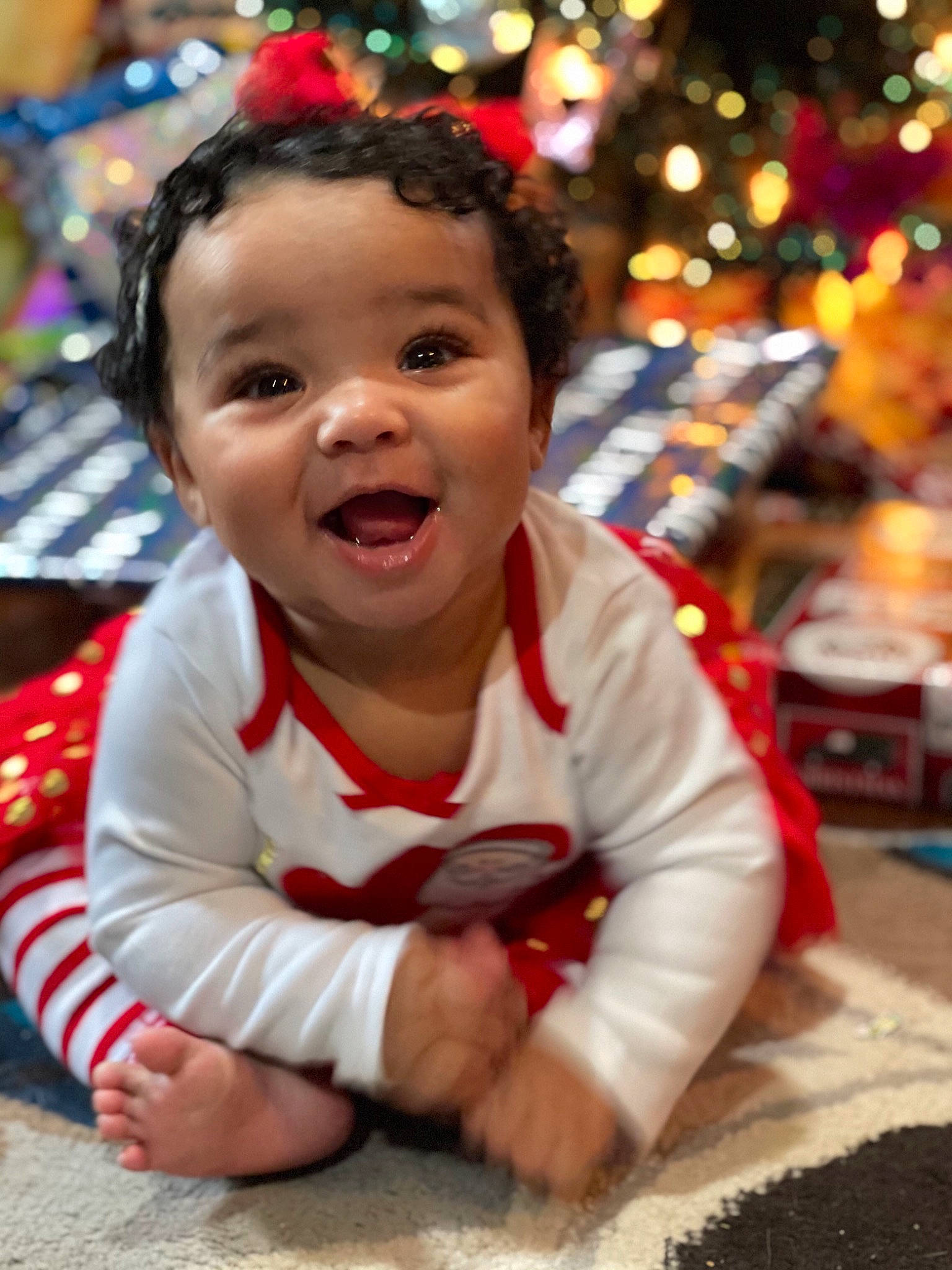 Liana is registered to the contest to win money with this photo: baby, baby_toddler_clothing, beauty, cheek, child, christmas_ornament, christmas_tree, eye, facial_expression, fun, happy, head, human, leaf, person, public_space, skin, smile, standing, toddler