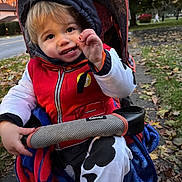 Michael joined the competition — help win amazing prizes! toddler, child, stroller, jacket, hoodie, autumn, leaves, sidewalk, outdoor, snack, smile, blanket, red, white, black, person, park, grass, happy, casual