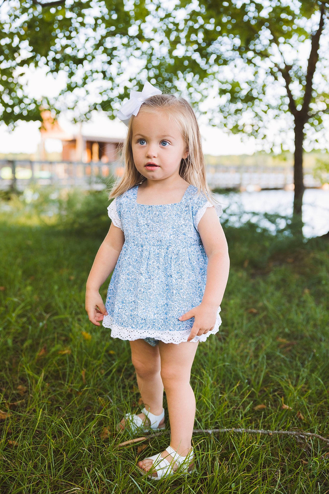 Parker is registered to the contest to win money with this photo: blond, brown_hair, child, day_dress, dress, electric_blue, grass, grassland, happy, human_leg, long_hair, pattern, people_in_nature, person, plant, skin, sky, standing, sunlight, toddler